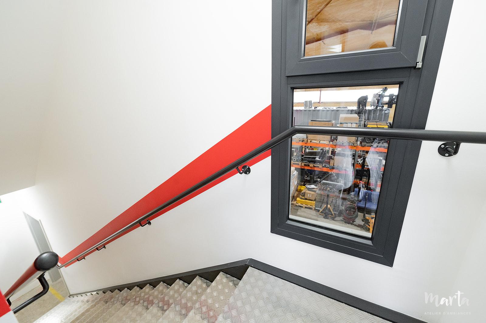 Vue de la sortie du bureau menant à la cage d'escalier, créant une transition fluide entre les espaces
